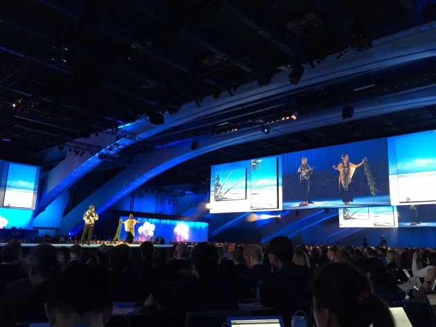 The Benioff Keynote at Dreamforce 14: The scene before it starts  The enormous crowd here is streaming into the main keynote with Marc Benioff here at Moscone Center on Tuesday. it's nearly 1pm PT and the main hall is filing up quickly. I'll live blog the event here as much as possible given that the Ethernet for industry analysts isn't working, but the private Wifi is, so hopefully we'll get most of what goes on here.  The biggest announcement so far, out of many, has been Salesforce's entry into the analytics and big data space, with their new Wave product. You can get a overview of the details on Wave from Larry Dignan on ZDNet and I'm sure we'll hear about it much more during the next few hours.  I'm also expecting the following during the keynote today: 1) A roundup and year-over-year update on Salesforce1 and its ecosystem, with lots of customer examples, 2) an overview of Wave (or its "Analytics Cloud") and the many 3rd party relationships they've already established, and 3) an even clearer and bigger vision for the Salesforce cloud. And plenty of philanthropy, maybe some politics, and of course, colorful Christian Louboutin shoes.  Wave: The new Salesforce analytics cloud #df14  1:11pm: The main hall doesn't look full yet, but there's definitely a lot of people vying for the desks in the analyst press area.  1:13pm: Now the always-excellent Peter Coffee is up doing a pre-amble on the keynote. Talking the usual bit about "amazing customers doing amazing things and bringing you in the next generation of technologies." Introducing the CIO of Telstra, who is talking about "creating a brilliantly connected future for everyone."  Peter Coffee onstage at Dreamforce 14  1:18pm: Just introduced the CIO of Ely Lilly talking with how Deloitte Digital is "helping them architect faster and faster." Talking about helping in compliance, manufacturing, inventory, and HR processes and gets the ROI faster using the Force platform. Coffee now talking about health and life sciences, where customer experiences for pharma apps are going right to the doctors.  1:22pm: Now have the a Hawaiian band on stage conducting a musical interlude. Didn't catch the band name.Hawaiian band and performers at Dreamforce 2014 #df14  1:26pm: Coffee: "One of the great things about Dreamforce is that you run into amazing people in the hallways." He says he just ran into George Zimmer in the halls (the famous voice and founder formerly of the Men's Wearhouse), who is now talking about his new business. The new business will be "high touch and high tech. Just like Salesforce with 1-1-1, and we'll make sure we value our customers, shareholders, and communities just like Salesforce." Coffee asks when we're going to hear about it. Sometime in the next few months, he says watch his Twitter account.  1:29pm: Now the Group CIO of Caterpillar is up, along with his Accenture sponsor. "Have been using Salesforce for many years, but has been fragmented across many operating groups." Accenture is providing the frameworks and processes to sort out a more consistent CRM implementation. Coffee: "New ways of things for a company doing what's it been doing for a long time." Says, "people want new ways to re-engineer what they're doing". Paul Daugherty, CTO, Group Chief Executive of Technology at Accenture is now talking "taking things to the next level, and industry solutions they bake onto the Salesforce platform. Connected products and connected dealers that they're helping Caterpillar 'bringing to life' using the Force.com platform. A good management consulting quote from Coffee: "Turning from a products focus to an outcome focus."  1:36pm: Now the chief strategist (I think) of Salesforce is talking with Coffee about how the Salesforce platform is evolving into many new disciplines, including supply chain. Coffee asking about what areas to focus on and follow up on later, including a Mystery X product that keeps being references. Says to be sure to watch what's going on with the marketing cloud, Internet of Connected Customers, analytics products (Wave I assume). Now welcoming the Ambassadors of Aloha from the island of Hawaii.